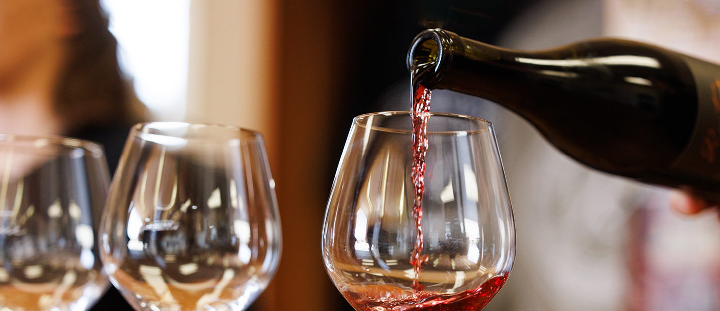 Landing page hero - Wine being poured from a bottle in a California tasting room